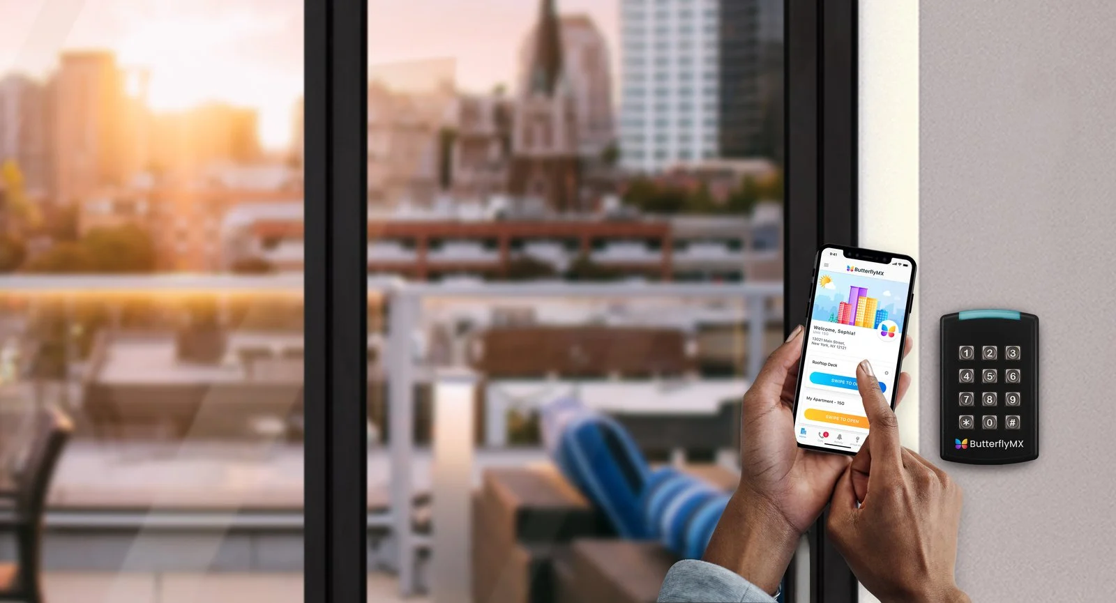 A resident holds a phone with the ButterflyMX app open beside a ButterflyMX keypad reader