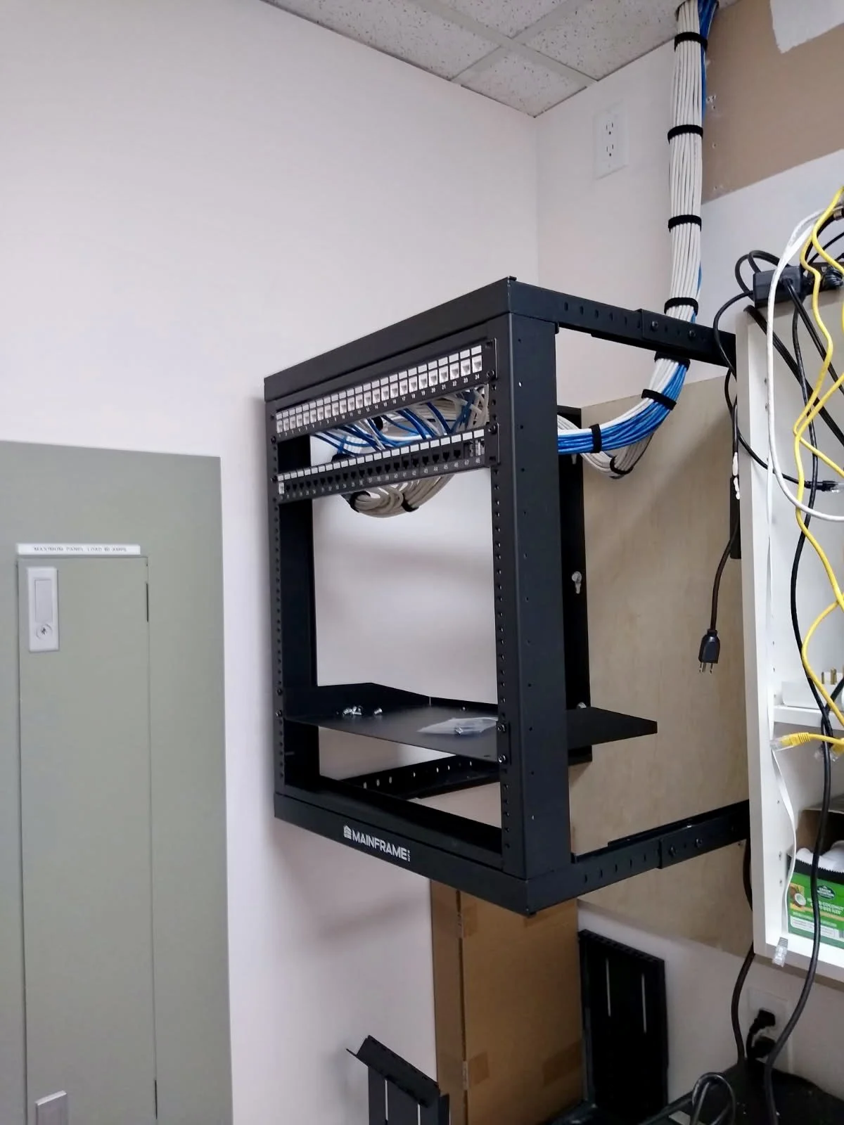 Wall-mounted server rack with blue network cables being bundled during cleanup