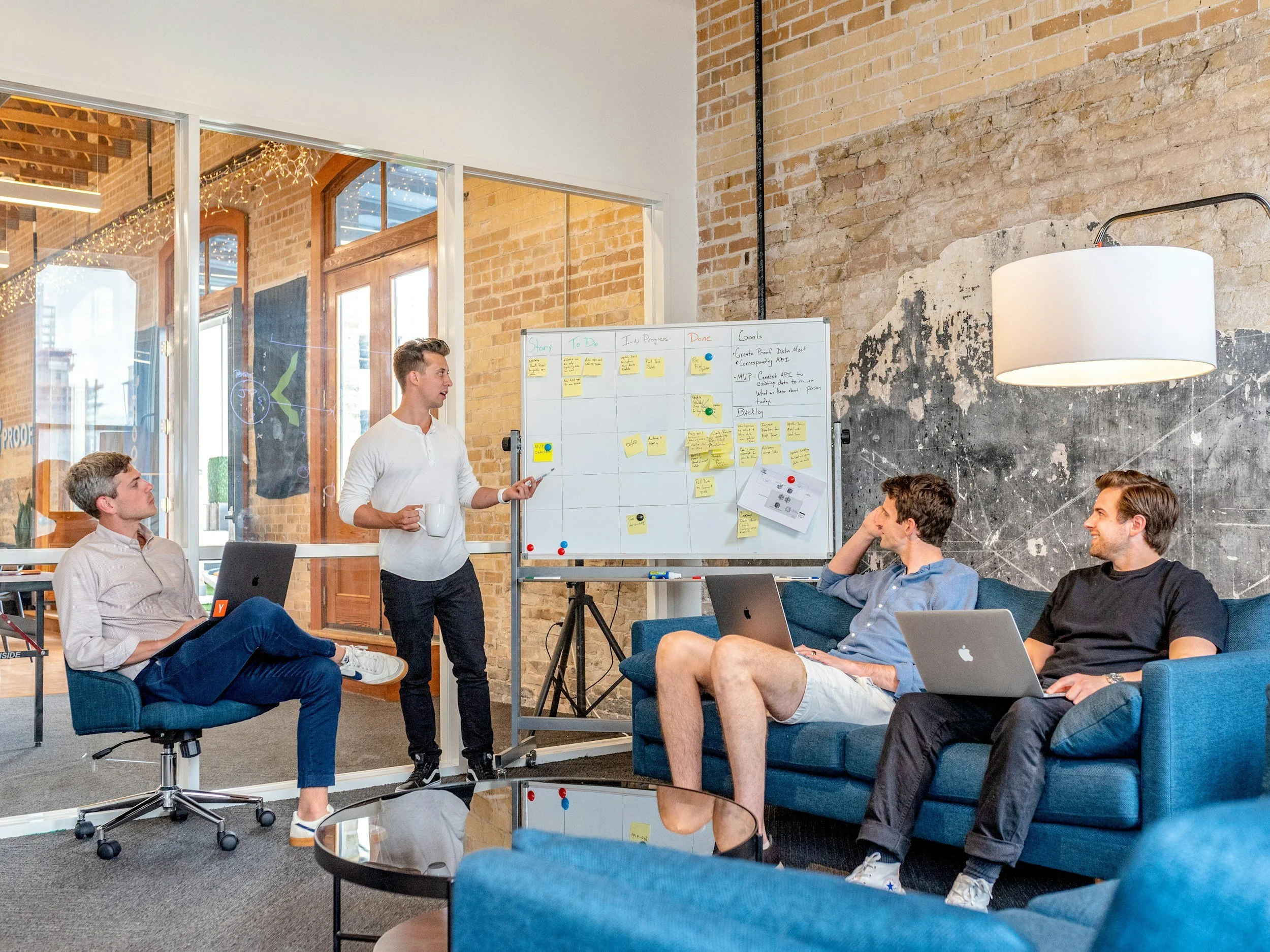 Four people collaborating in an office with a sticky note whiteboard